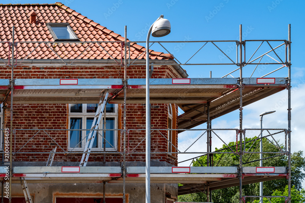 Fototapeta premium Restoration of a historic brick building with facade scaffolding in summer