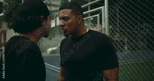Cuadro en lienzo Close-up of two Hispanic men in heated street argument near metal fence, one sho