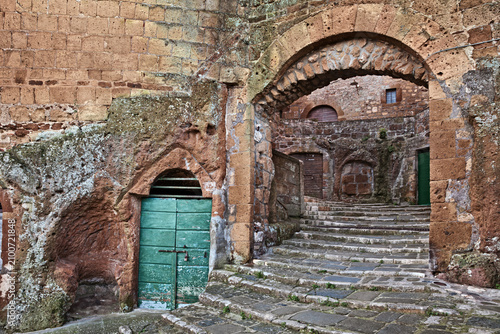 Pitigliano, Tuscany, Italy: Medieval city gate Porta di Sovana with stone stairs and cellar doors, in the village founded in Etruscan times