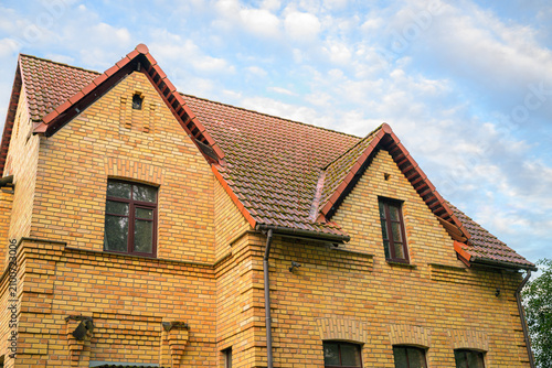 Εκτύπωση καμβά Old brick house with red tiled roof under blue sky