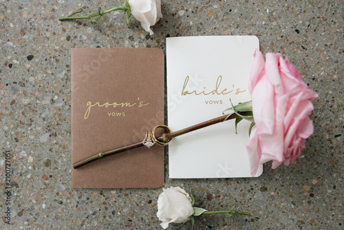 Foto His and hers wedding vow books with gold rings and rose stem