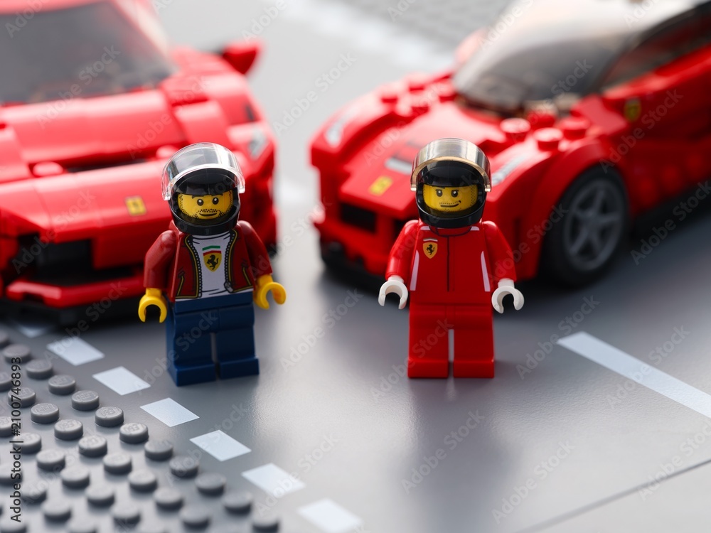 Obraz premium Tambov, Russian Federation - July 12, 2026 Two Lego Ferrari driver minifigures standing on a road baseplate with red Ferrari sports cars in the background. Lego Speed Champions