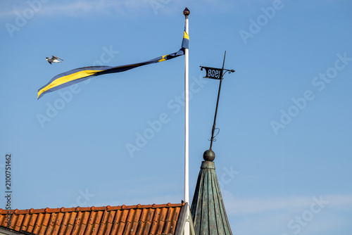 Swedish pennant flag flying on flagpole near historic weather vane in Karlskrona, Sweden