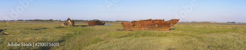 Fotografie Panoramic view of decaying historic shipwrecks stranded in the green salt marshes at Fleetwood, glowing under a bright, clear coastal sky