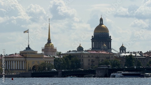 The golden dome of St. Isaac's Cathedral and the Admiralty spire tower over the city skyline along the Neva river in St. Petersburg.