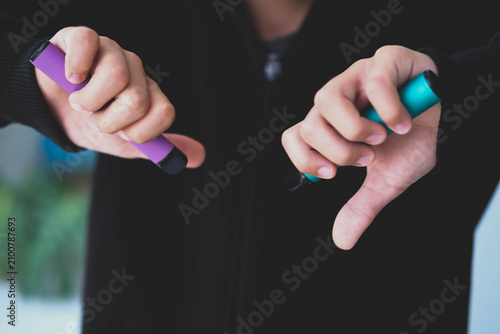 A teenager holds disposable e-cigarettes and gives a thumbs-down gesture. The dangers of smoking.