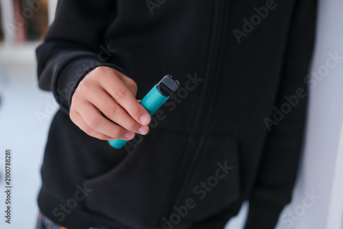 A teenager is holding a violet vape. A dangerous addiction. Vaping among teenagers.