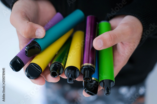 A child is holding many colorful vapes. A dangerous addiction.=
