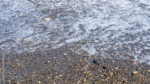 Принти на полотні White sea foam spreading across a pebble shore