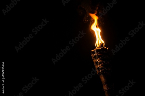 A single burning torch creating a focal point of light in darkness.