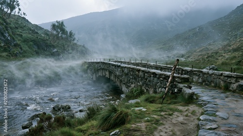 Foggy stone footbridge crossing a highland stream in overcast light