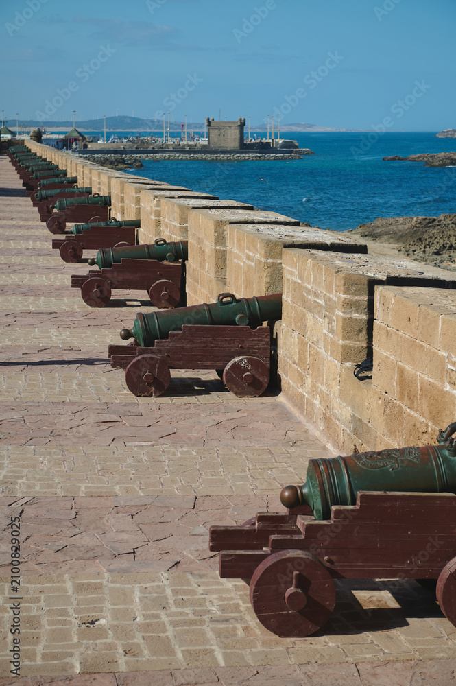 Fototapeta premium Row of historic cannons along Essaouira medina sea wall overlooking harbor and Atlantic coast in Morocco