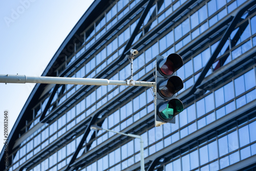 Φωτογραφία Traffic light displaying green signal against modern glass building facade with