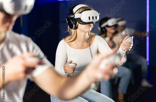In dark hall of entertainment center, young guys and girls talking about spending time in virtual game. Non-existent reality, immersion in fantastic world of game