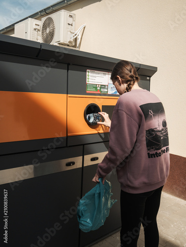 Krotoszyn, poland - 20 06 2026: Young woman inserting a plastic water bottle into an automated reverse vending machine for recycling and bottle deposit refund