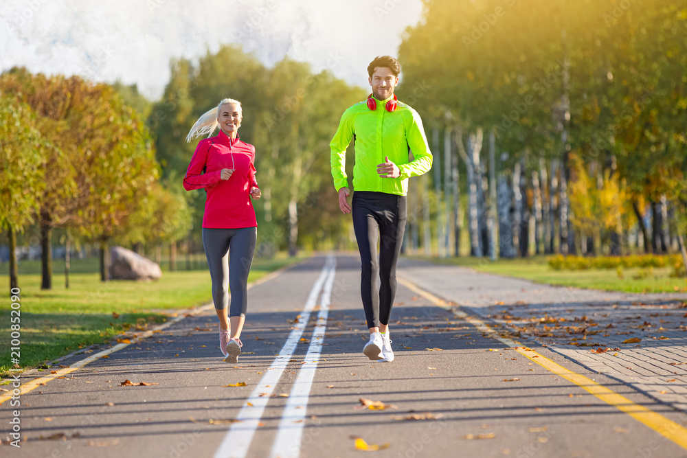 Fototapeta premium Running Couple Happily Jogging Together Outside as Runners Training Outdoors Working Out in City Outdoors.