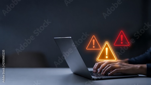 Critical warning symbols pop up from laptop screen as user types, highlighting cybersecurity risk and data breach.