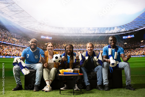 Φωτογραφία Happy soccer fans on couch cheering after goal, feeling like they are inside stadium, cheerful football supporters together at home enjoying immersive match day during TV broadcast