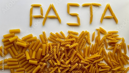 Foto Horizontal flat lay of the word PASTA spelled out using penne noodles above a variety of uncooked pasta types including fusilli, penne, and rigatoni on a clean white background