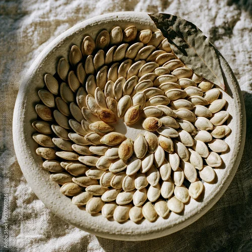 Obraz Toasted pumpkin seeds arranged in radial spiral in ceramic bowl