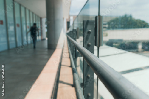 Modern building corridor railing with a blurred walking person in the background