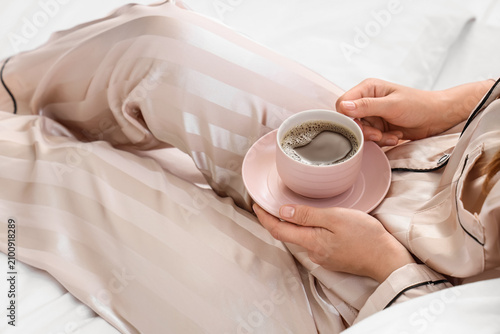 Woman in silk pajamas holdi...