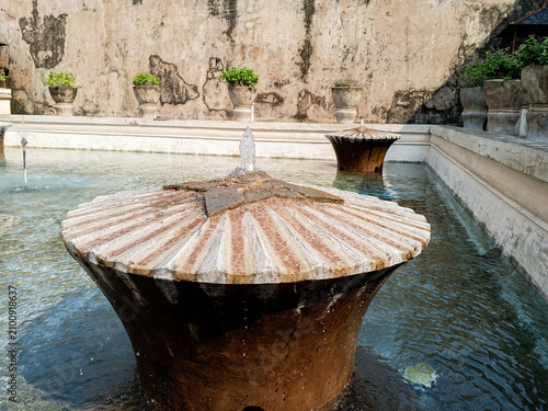 Historic fountain flows inside the bathing pool courtyard of Taman Sari Water Castle in Yogyakarta, Indonesia, photographed in daylight to show aged masonry, water features, and royal heritage