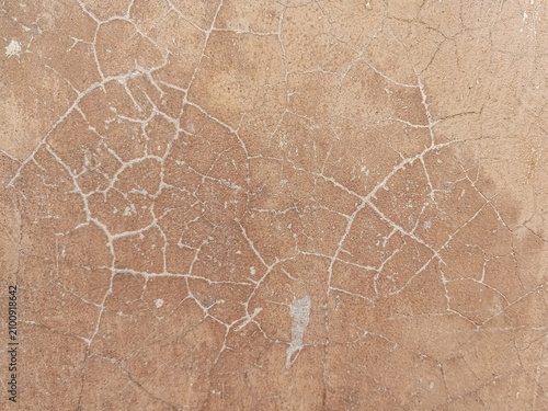 Close-up of a weathered beige plaster wall with irregular cracks and aged texture, photographed evenly as a natural abstract background for architecture, renovation, decay, and grunge concepts.