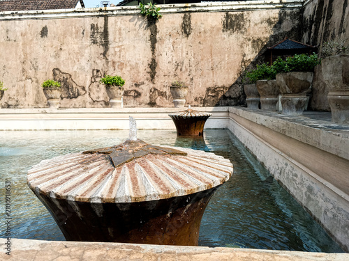 Historic fountain flows inside the bathing pool courtyard of Taman Sari Water Castle in Yogyakarta, Indonesia, photographed in daylight to show aged masonry, water features, and royal heritage