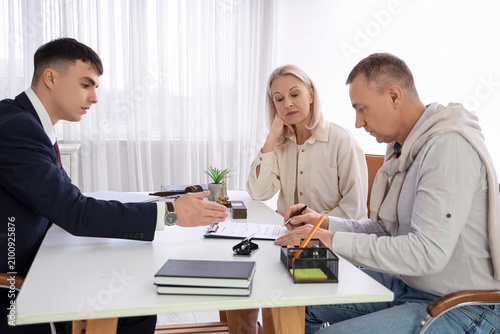 Фотография Male lawyer with mature couple signing divorce decree at table in office