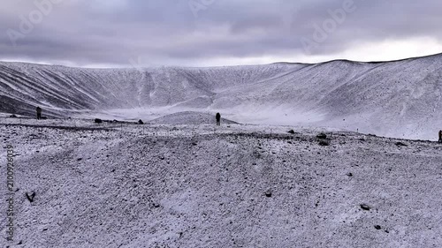 Drone flyover of explorers on a snowy volcano crater edge in Hverfjall, Myvatn, Iceland