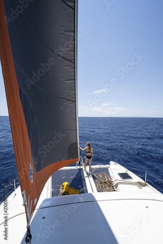Young woman standing by the foresail, Sailing a sailing catamaran, Dodecanese, Greece