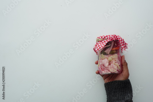 Foto A person grips a jar filled with various food items
