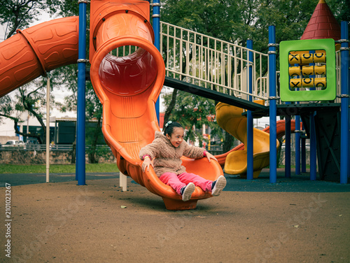 Child slides down an orange playground slide