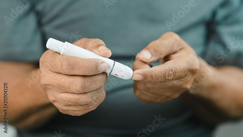 Canvastavla Close-up of a senior adult performing a finger prick with a lancet device for blood glucose testing at home