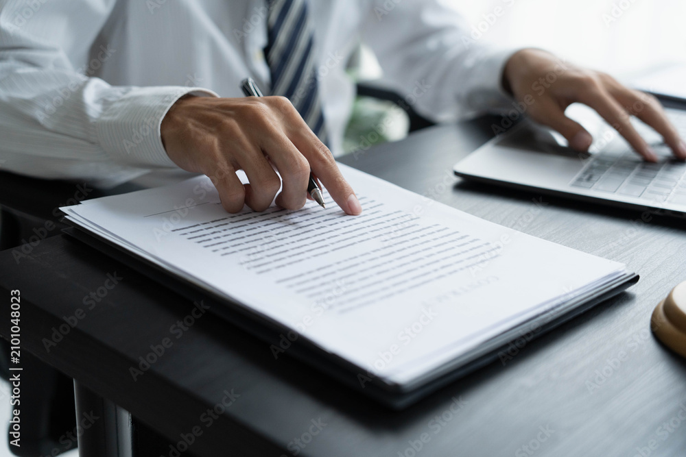 Fototapeta premium Lawyer checking documents and typing on laptop
