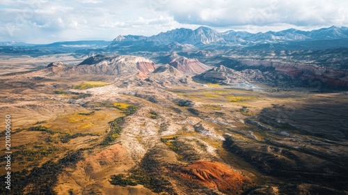 Aerial view of a vast, arid landscape with colorful rock formations and distant mountains