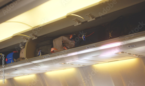 Fotografía Carry-on luggage in the overhead bin of a commercial airplane