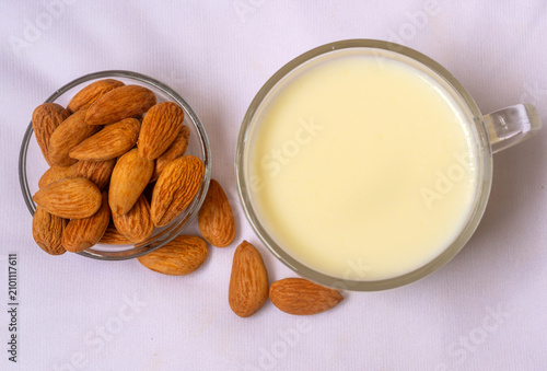 Obraz na płótnie Almond milk in a glass cup with a glass bowl almond nuts on white background