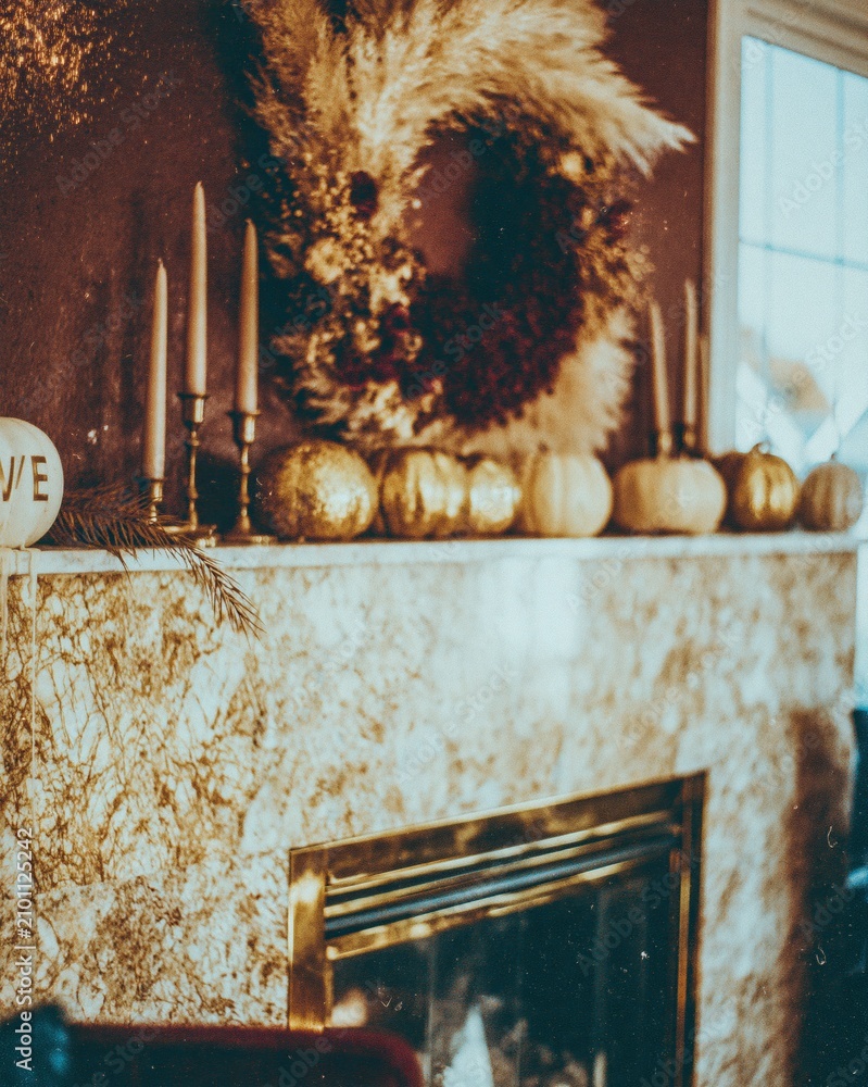 Obraz premium Opulent veined marble fireplace mantel decorated with a dried flower wreath and gold pumpkins for elegant autumn home decor and seasonal interior design