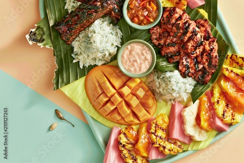 Filipino kamayan feast with grilled meat, mango, and rice on banana leaves, a vibrant boodle fight spread for cultural dining and food marketing