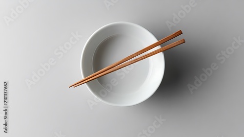 Empty white bowl with chopsticks. Asian dining utensils on plate.