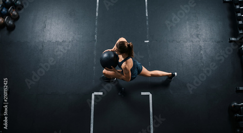 Woman doing a medicine ball lunge in a dim gym
