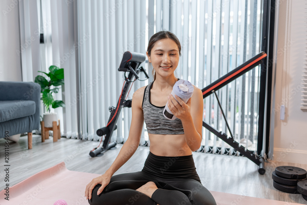 Fototapeta premium A fit young woman performs kettlebell strength training, grip exercises, mobility work, and post workout recovery at home, promoting functional fitness, muscle endurance and healthy active lifestyle.