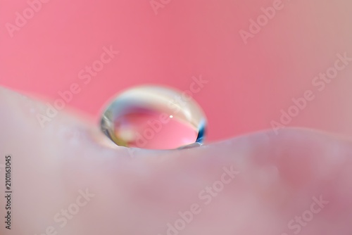 Water droplet on pink surface with rainbow effect