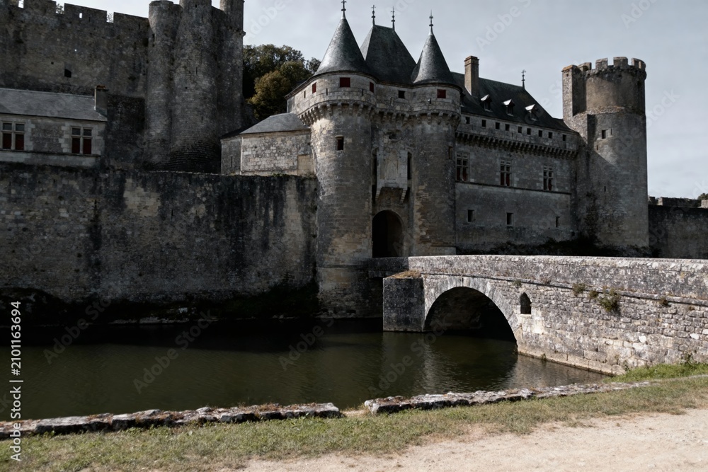 Obraz premium Medieval stone castle with moat and arched bridge, featuring towers and fortified walls