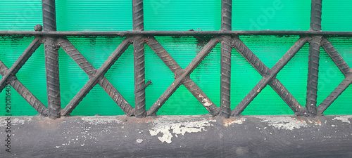 Konstfotografi Close-up of a black wrought iron fence with a geometric pattern, set against a vibrant green polycarbonate background sheet