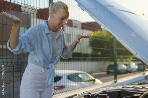 Cuadro en lienzo Woman experiencing car trouble on a sunny day, looking frustrated with car engin