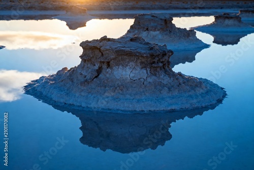 Tufa formations reflected in calm water at sunrise