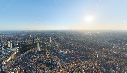 Istanbul, Turkey. Panoramic aerial view over the European city center skyline with modern glass skyscrapers rising above dense terracotta rooftops, golden sunset light and clear sky
